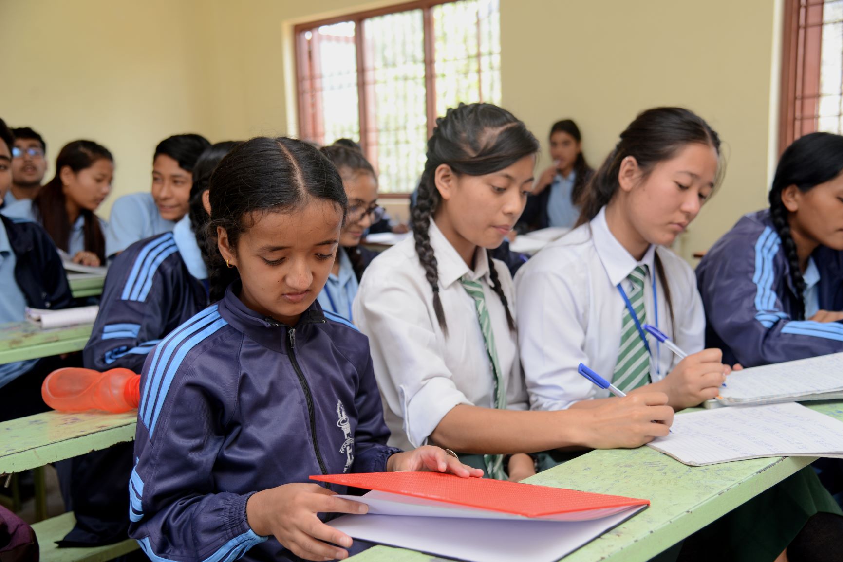 students in a classroom opening their notebooks