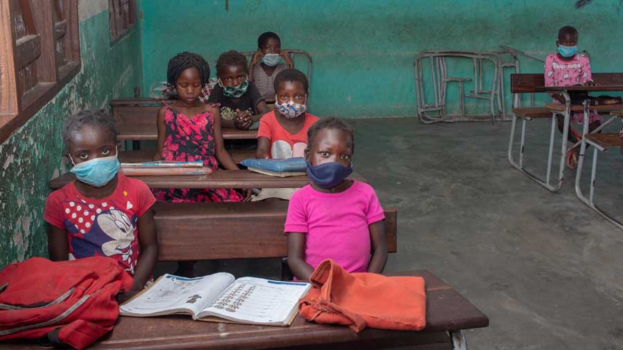 Schoolgirls back to school in a classroom, distanced and wearing face masks, protecting themselves from COVID-19. Manica, Mozambique. Photo: Shutterstock
