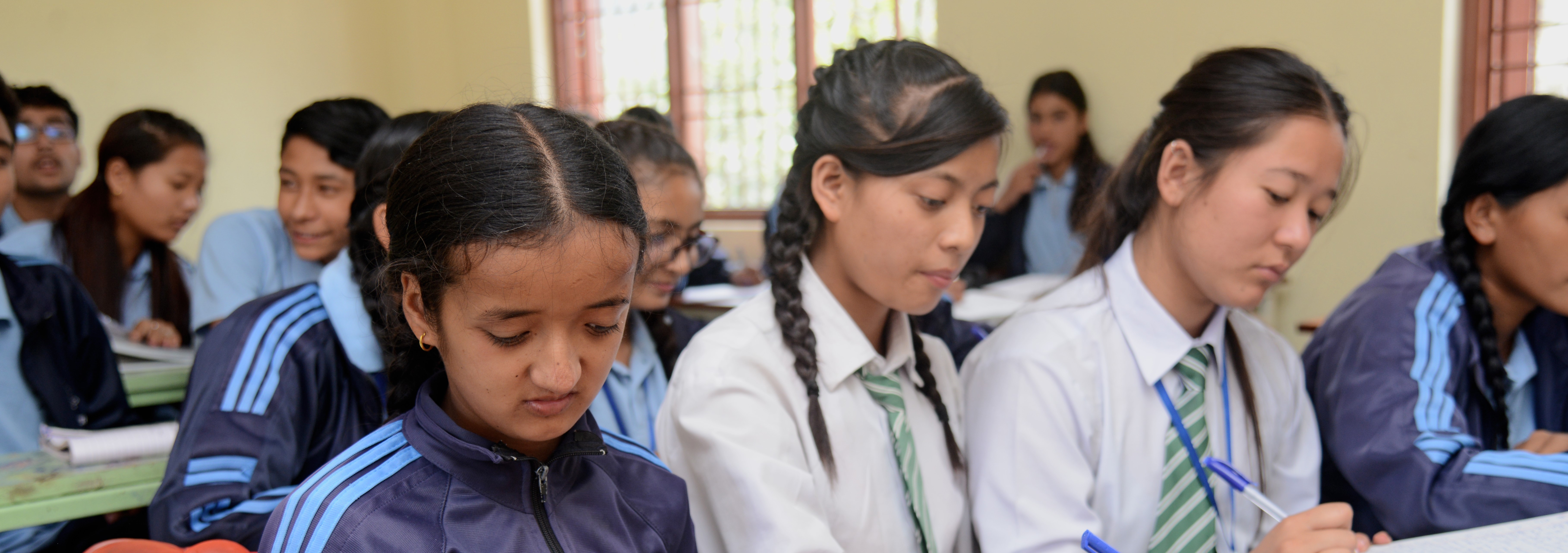 students in a classroom writing on their notebooks